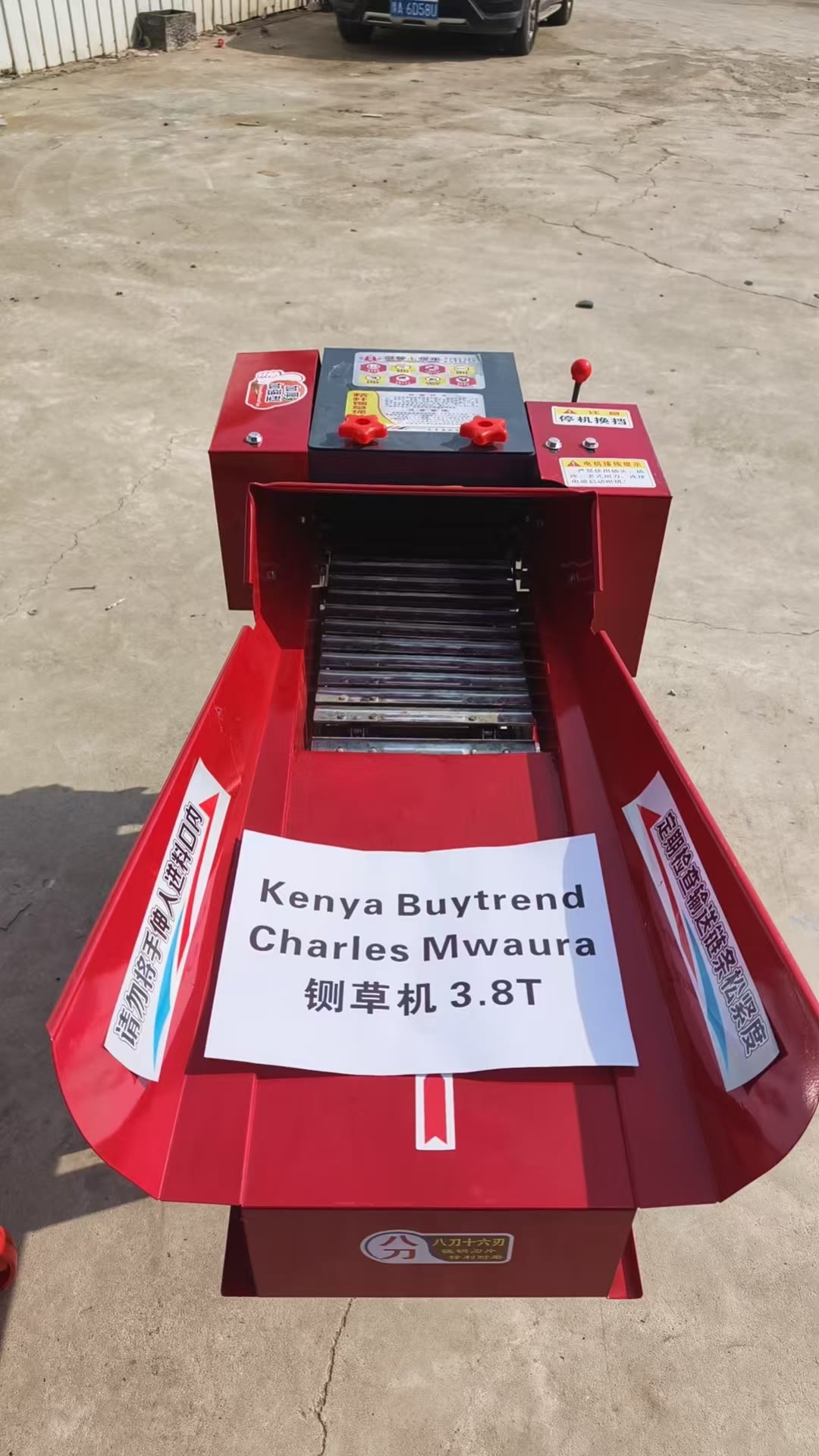 A finished red LUCTORC 3.8 t/h chaff cutter in a factory yard, its infeed tray carrying a printed label that reads Charles Mwaura, chaff cutter 3.8T, for Kenya