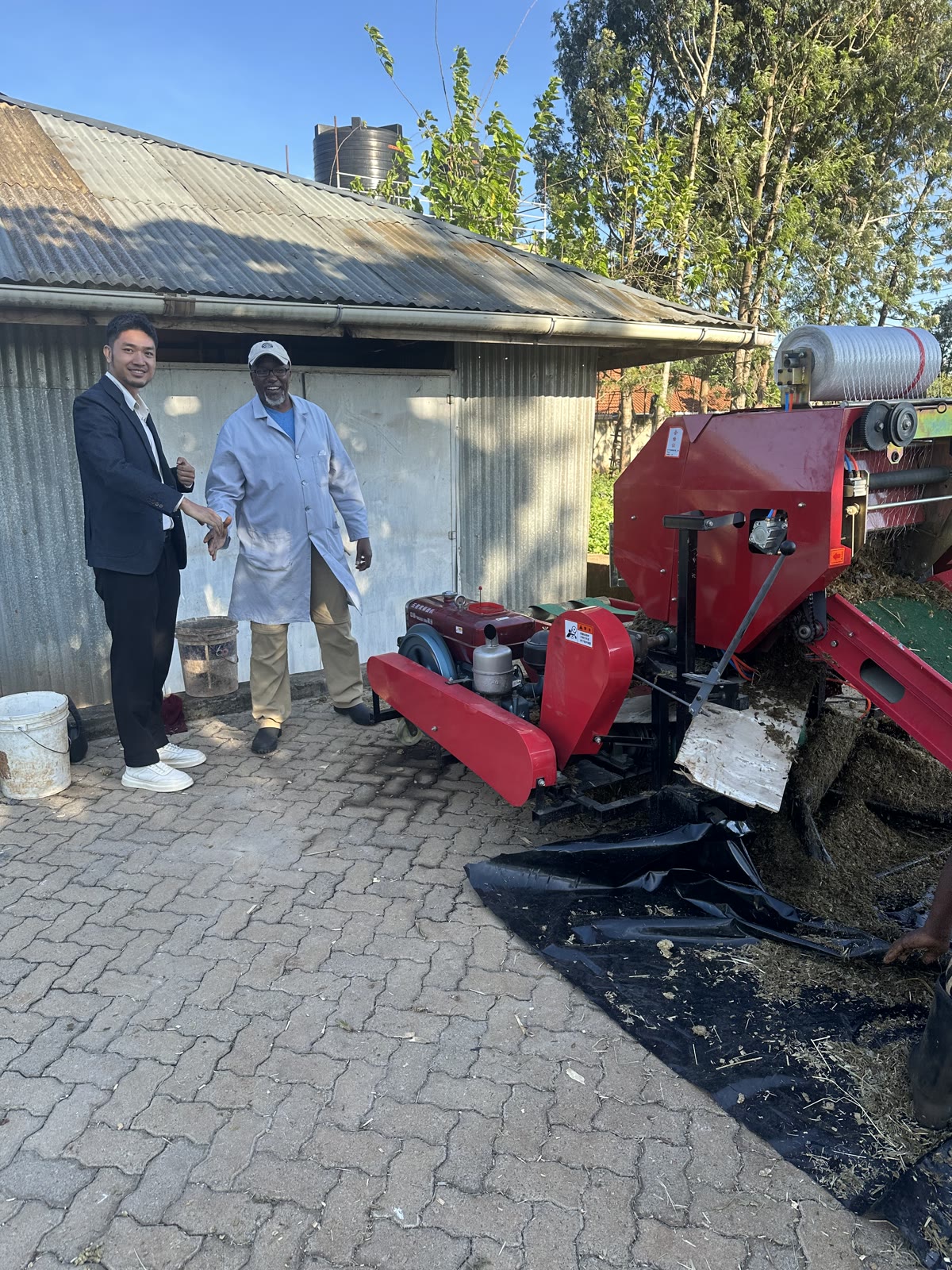A Kiambu farm customer and a machinery representative beside the diesel silage baler wrapper after the on-site test